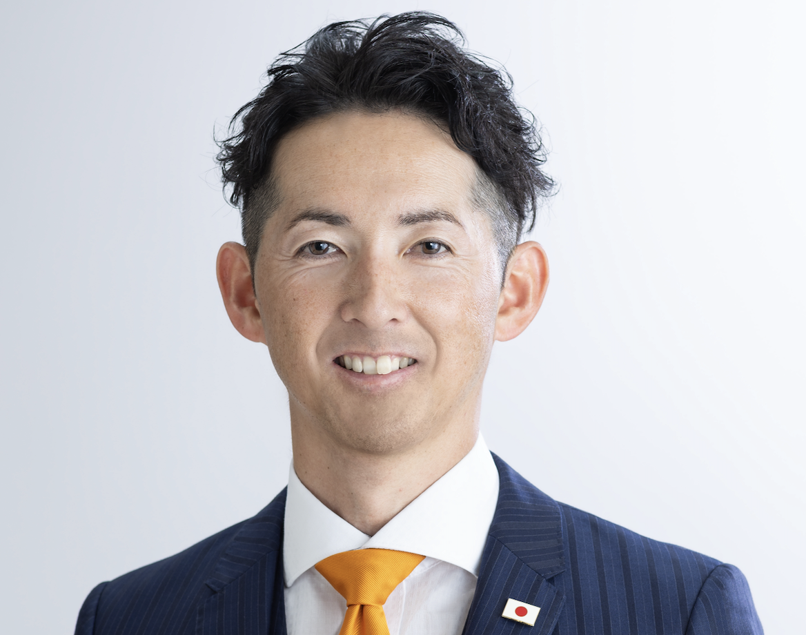 スーツ姿で笑顔を見せるいざき博幸さん